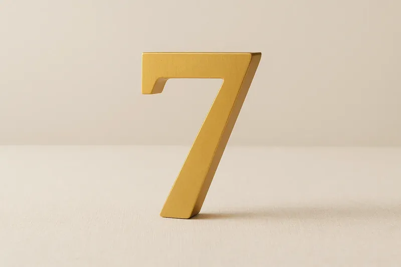 Large golden seven symbol on cream background with soft shadow